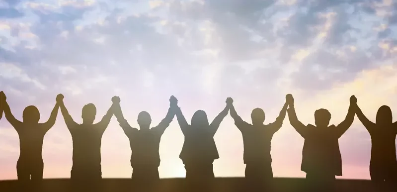 group of people holding hands in the sunset